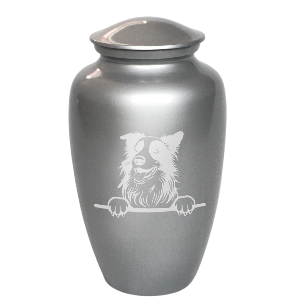 A metallic silver pet urn with a lid, featuring a white engraved illustration of a dog peeking over a barrier on the front.