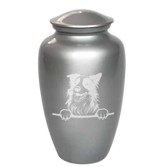 A metallic silver pet urn with a lid, featuring a white engraved illustration of a dog peeking over a barrier on the front.