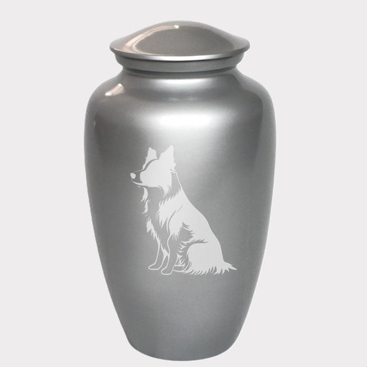 A silver metal cremation urn with a laser engraved image of a sitting border collie dog on the front.
